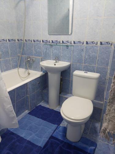 a blue tiled bathroom with a toilet and a sink at Однушка в белом на Радостовца in Almaty