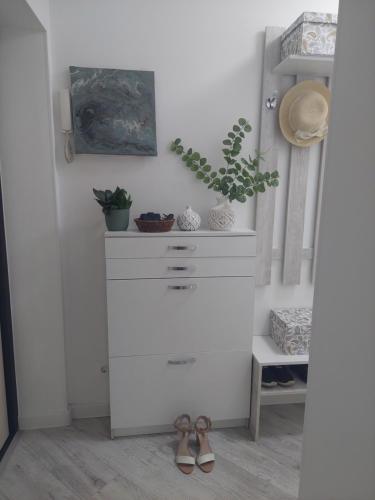 a white dresser with a potted plant and shoes at Однушка в белом на Радостовца in Almaty