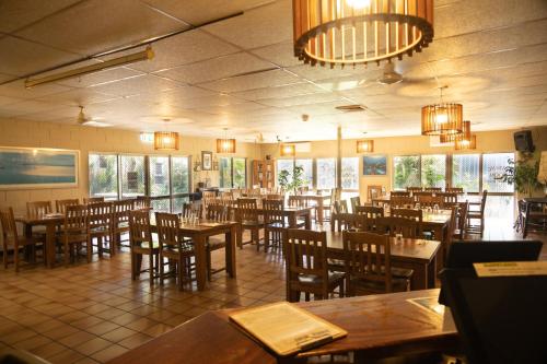 un restaurant avec des tables et des chaises en bois ainsi que des fenêtres dans l'établissement Wongai Beach Hotel, à Horn