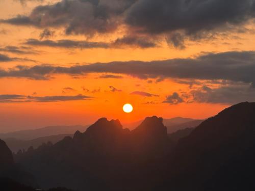 a sunset in the mountains with the sun setting at Zhangjiajie National Park Nvue Resorts in Zhangjiajie