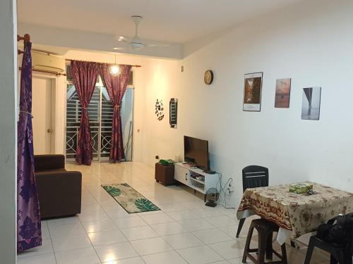 een woonkamer met een tafel en een tv. bij 3rd floor apartment with 2 bedroom and no elevator in Kota Bharu