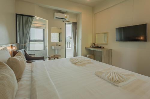 a bedroom with a white bed with a flat screen tv at Ang Pao Hotel Phuket in Phuket Town