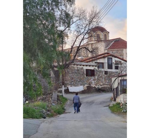 a man walking down a road in front of a building at THE ROCK HOUSE - Beautiful countryside with mandarins oranges and olive trees,. Near Limassol at Eptagonia village. in Ephtagonia