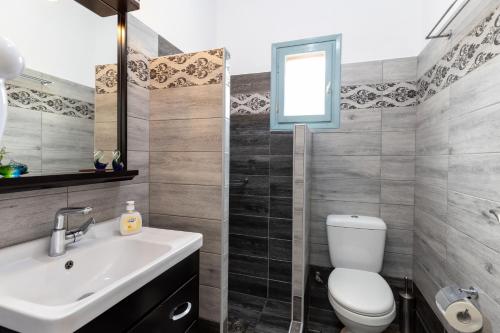 a bathroom with a sink and a toilet and a window at Peris Rooms in Sifnos