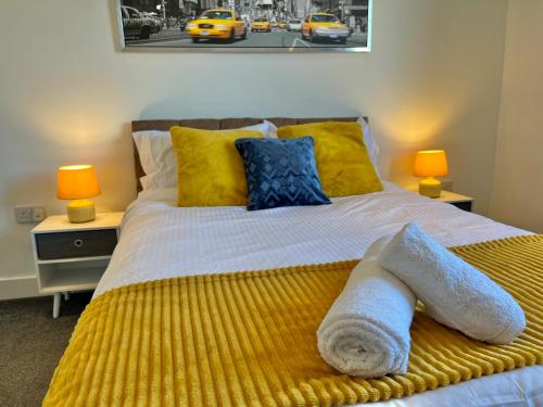 a bedroom with a bed with yellow and blue pillows at Lovely Serviced Apartment - Near Doncaster Hospital in Doncaster