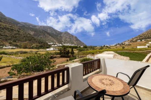 a balcony with a table and chairs and mountains at Peris Rooms in Sifnos