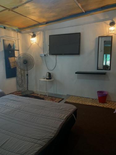 a bedroom with a bed and a flat screen tv at SABAYA HOMESTAY in Balik Pulau