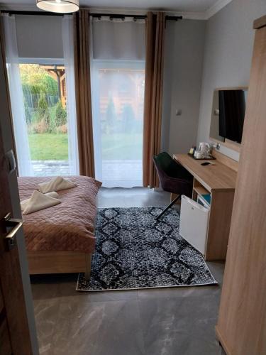 a bedroom with a bed and a desk and a television at VILLA EDEN USTKA wypoczynek dla dorosłych in Ustka