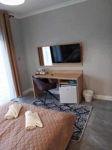 a bedroom with a bed and a desk with a television at VILLA EDEN USTKA wypoczynek dla dorosłych in Ustka