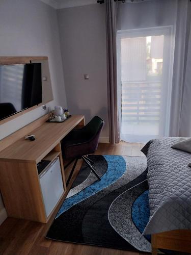 a bedroom with a bed and a desk with a television at VILLA EDEN USTKA wypoczynek dla dorosłych in Ustka