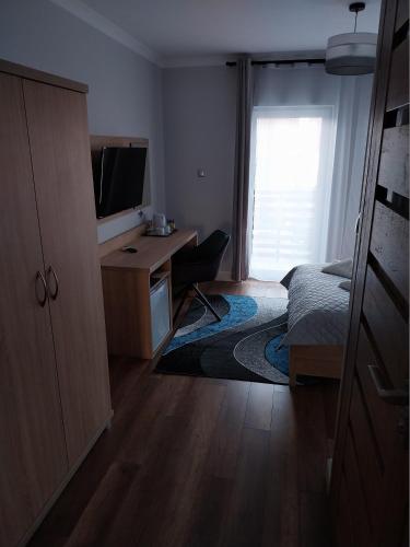 a bedroom with a desk and a bed and a television at VILLA EDEN USTKA wypoczynek dla dorosłych in Ustka