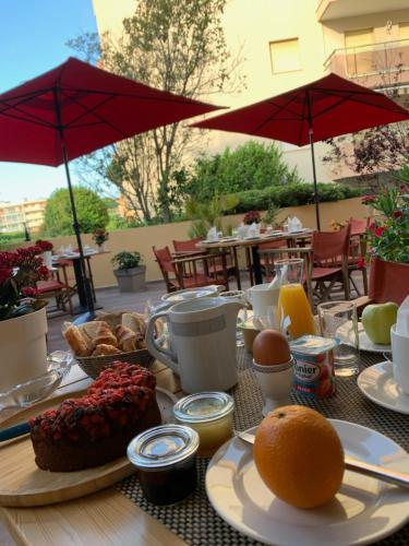 a table with breakfast food on a table with umbrellas at Le Petit Prince in Sainte-Maxime