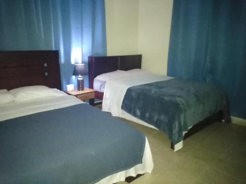 ein Hotelzimmer mit 2 Betten und einem Tisch mit einer Lampe in der Unterkunft Boquetelandia in Alto Boquete