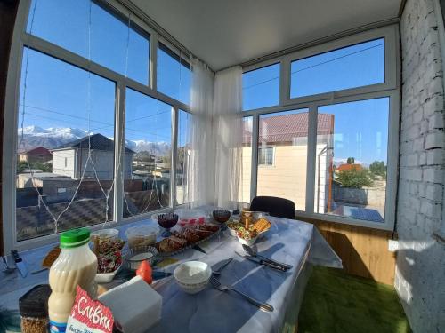 een tafel met eten in een kamer met ramen bij Guest house B&B in Kochkorka