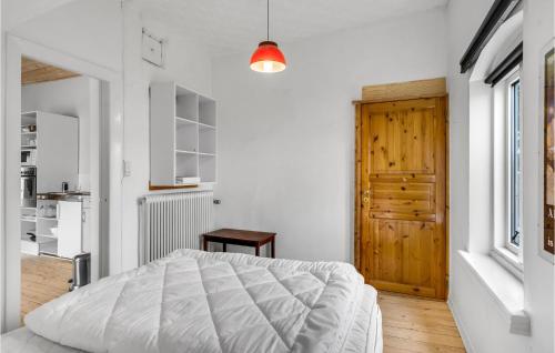 a white bedroom with a bed and a wooden door at Gorgeous Apartment In Hjer With Kitchen in Højer