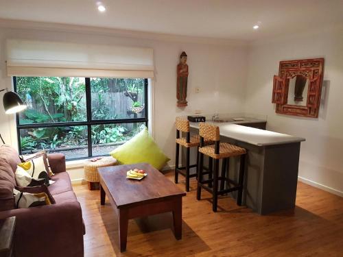 a living room with a couch and a kitchen at Dolphin Cottage Garden Studio in Huskisson