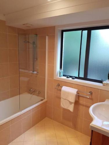 a bathroom with a shower and a tub and a sink at Dolphin Cottage Garden Studio in Huskisson