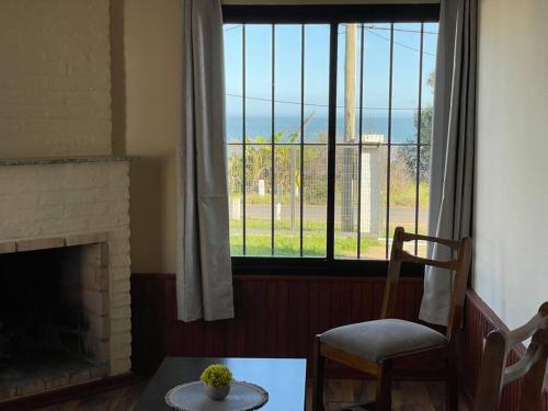 a living room with a fireplace and a chair and a window at Casa Alquiler Cuchilla Alta 1 in Cuchilla Alta