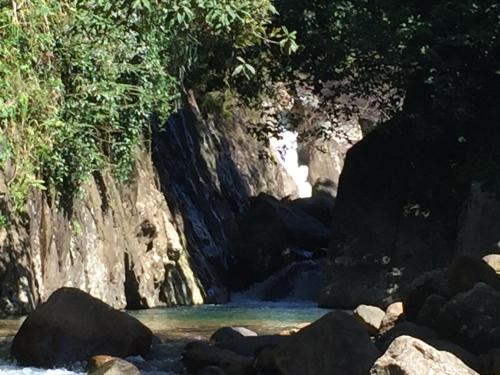 a river with rocks in front of a mountain at Rohana Estate Lodging & Camping in Kandy