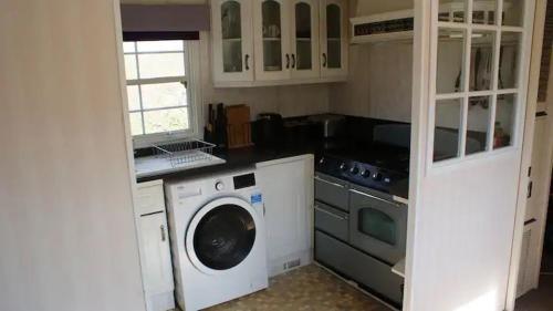 a kitchen with a washing machine and a washer at Bridge Farm Caravan in Buxton