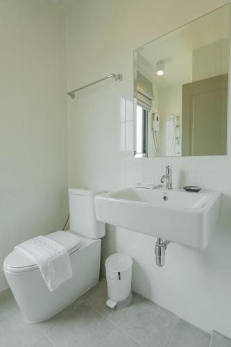 a white bathroom with a toilet and a sink at Ang Pao Hotel Phuket in Phuket Town