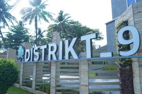 a sign in front of a building with palm trees at Distrikt 9 in Palakkad
