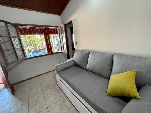 a living room with a gray couch with a yellow pillow at Casa Alquiler Cuchilla Alta 2 in Cuchilla Alta