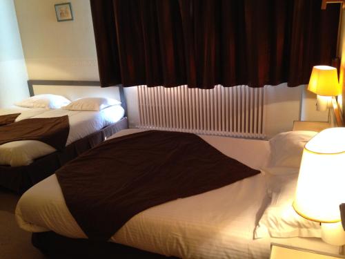a hotel room with two beds and a window at Hôtel Continental in Vierzon