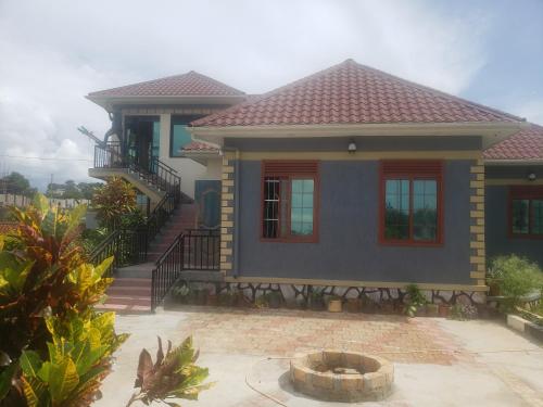 a small blue house with a porch and stairs at Alice Gardens & Campsite in Entebbe