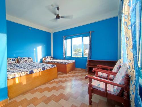 a blue room with two beds and a bench at Tranquil Water Guest House in Pokhara