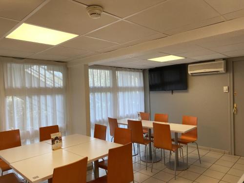a conference room with tables and chairs and windows at Premiere Classe Lyon Sud - Chasse Sur Rhône in Chasse-sur-Rhône
