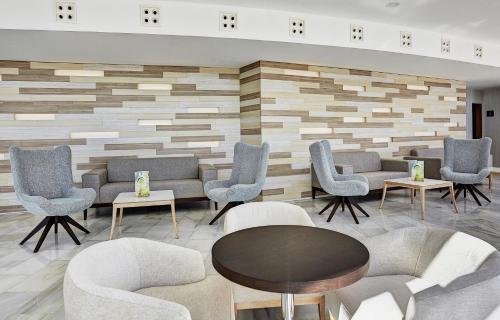 a waiting area with chairs and tables in a lobby at Grupotel Acapulco Playa - Adults Only in Playa de Palma