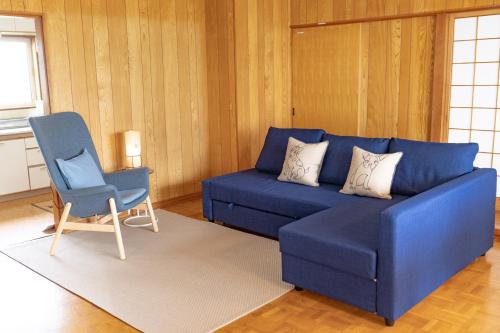 a blue couch and a chair in a living room at Furano Yukinko House in Furano
