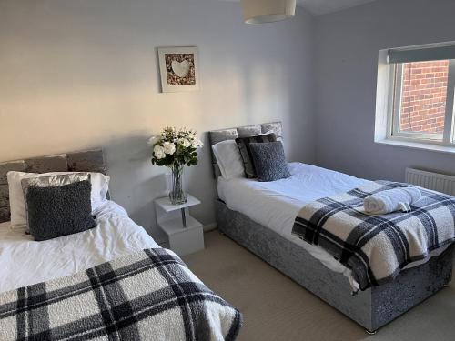 een slaapkamer met 2 bedden en een vaas met bloemen bij Modern 3 bed house 2 parking spaces contractors welcome in Stevenage