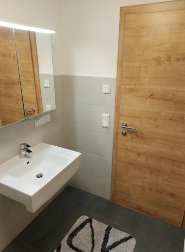 a bathroom with a sink and a wooden door at Ski & Alps Tamsweg in Sauerfeld