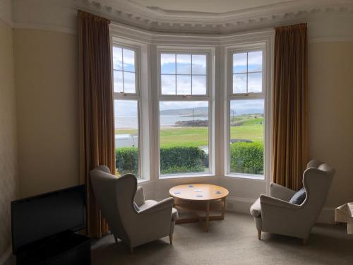 a room with chairs and a table and a large window at 4 Kames Bay in Millport