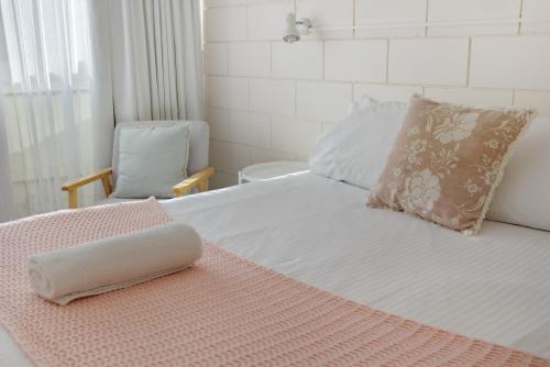 a bedroom with a bed with a pillow and a chair at Penguin Mews Merimbula in Merimbula