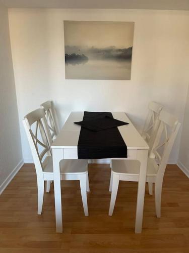 einen weißen Esstisch mit Stühlen und ein Gemälde in der Unterkunft City Appartment 2 Krefeld 20km DUS Airport/ Messe in Krefeld