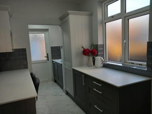 a kitchen with a counter with red flowers in a vase at Peaceful Home in Surbiton, Surrey, Greater London- Free parking in Surbiton