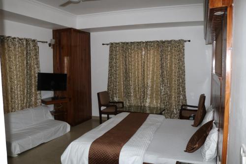 Cette chambre comprend un lit et une télévision. dans l'établissement The Abhinandan, à Mussoorie