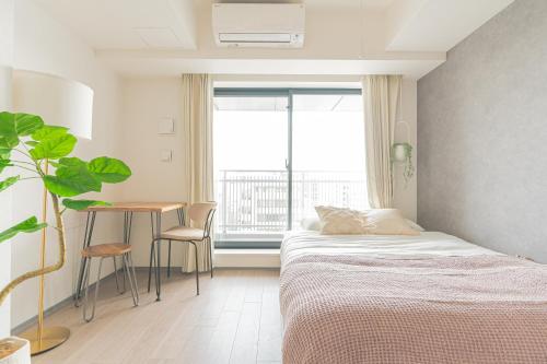 a bedroom with a bed and a table and a window at i-rent京急蒲田 in Tokyo