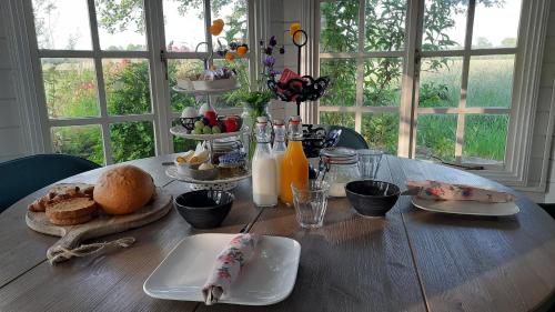 una mesa de madera con alimentos para el desayuno y bebidas. en Pipowagen 't Strunerke, en Augustinusga