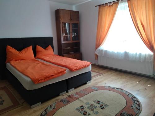 een slaapkamer met een bed met oranje kussens en een raam bij Casa Simona in Vişeu de Sus