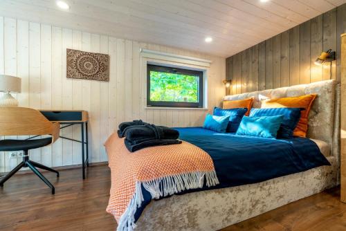 a bedroom with a bed with blue and orange pillows at SHANTI FOREST HOUSE Guest house with mirror sauna 