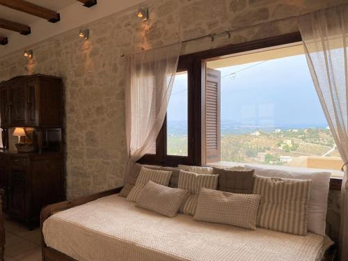 a bed in a room with a large window at Malvazia Residence in Kamilari