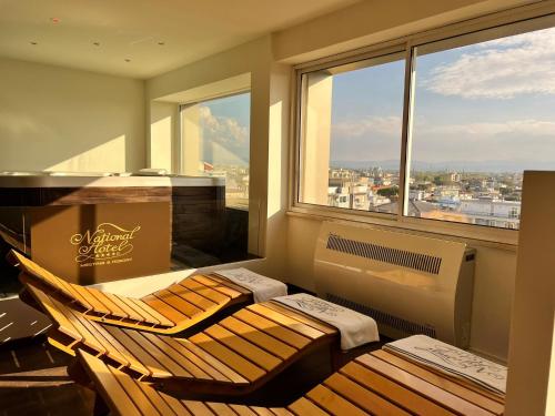 a room with a chair and a piano in front of a window at National Hotel in Rimini
