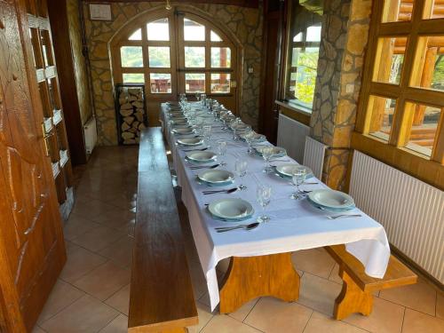 einen langen Tisch mit Tellern und Weingläsern darauf in der Unterkunft Wood house Marilla in Virovitica
