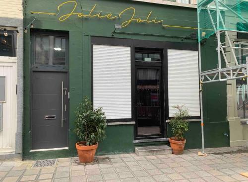 a green building with two potted plants in front of it at Un sommeil paisible in Brussels
