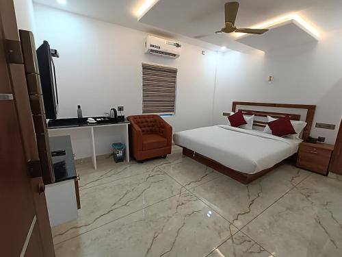 a bedroom with a bed and a chair and a desk at MARINA SUITES AIRPORT HOTEL in Cochin
