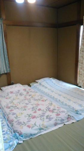 a bed with a floral blanket on top of it at "Cherry House" is Direct to Narita,Haneda AP, Disney, Asakusa, Skytree Tower, Tokyo in Matsudo